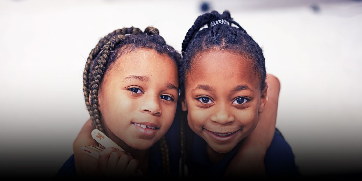Smiling students with their arms around each other in class